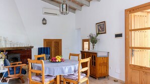 Un coin repas avec une table ronde, des chaises en bois, une cheminée et un buffet en bois.