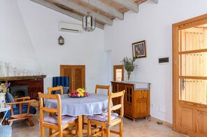 A dining area with a round table, wooden chairs, a fireplace, and a wooden cabinet.