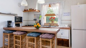 Une cuisine dotée d’un îlot central, de tabourets de bar, d’un four à micro-ondes, d’une machine à café et d’un réfrigérateur.