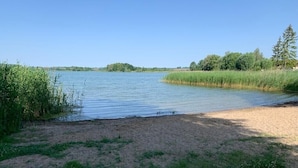 Een rivieroever met een zandstrand en grasvelden.