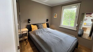 Een slaapkamer met een bed, nachtkastjes, een raam en een spiegel.