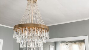 Un lustre orné de détails en cristal est suspendu à un plafond blanc.
