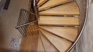 Una escalera caracol con escalones de madera y barandillas de metal.