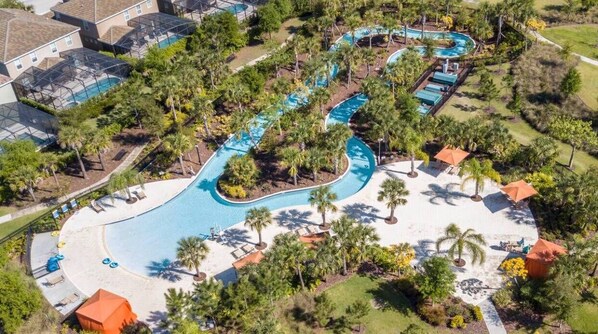 Relax by the resort's winding pool surrounded by palm trees and a sandy beach.