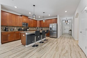 Enjoy cooking in this well-equipped kitchen with a central island, stainless steel appliances, and wooden cabinetry.