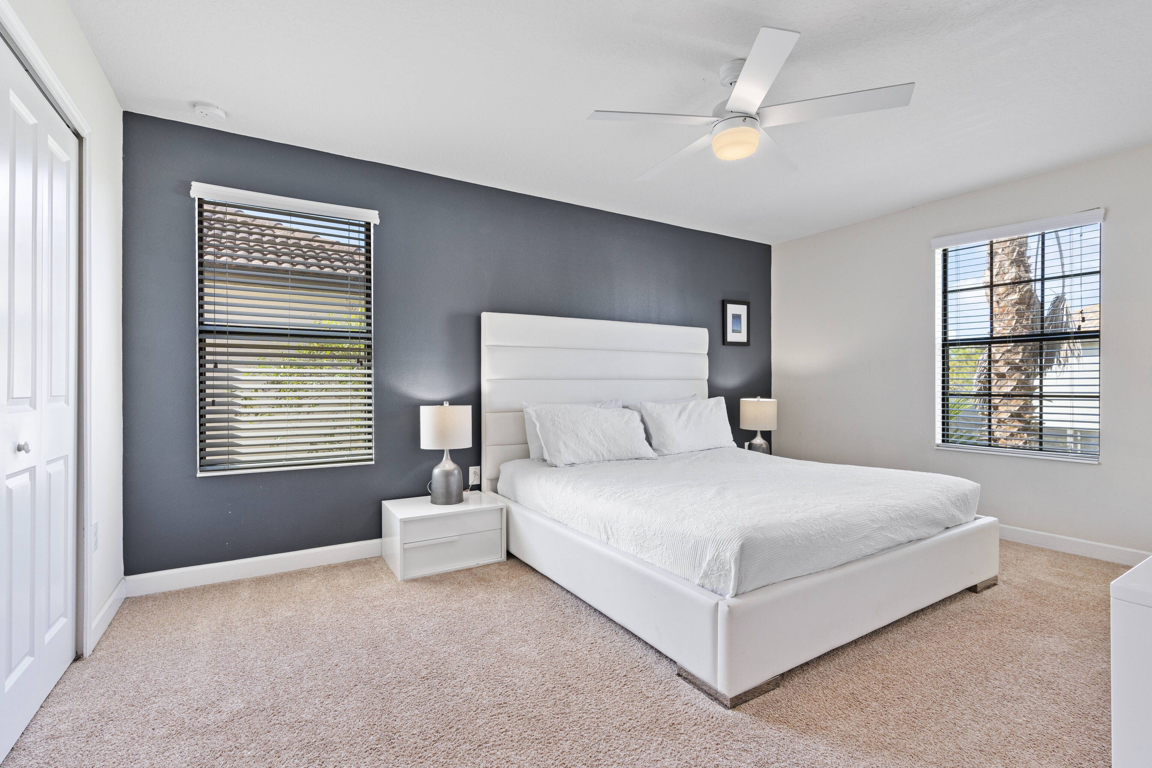 A bedroom with a large bed, a ceiling fan, and two bedside tables with lamps.