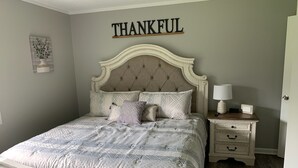 Een slaapkamer met een bed, een nachtkastje, een wandbord en een wanddecoratie.