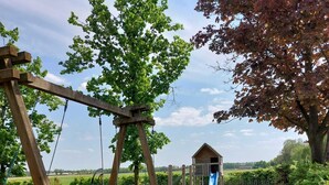A playground with a swing set, a slide, and a small wooden structure. - Group accommodation 32 pers, near Efteling and Beekse Bergen (Haghorst)