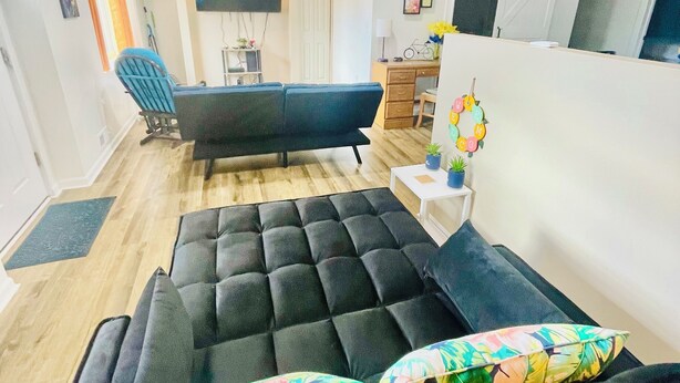 A modern living room with a black sofa, a small coffee table, and a TV mounted on the wall.