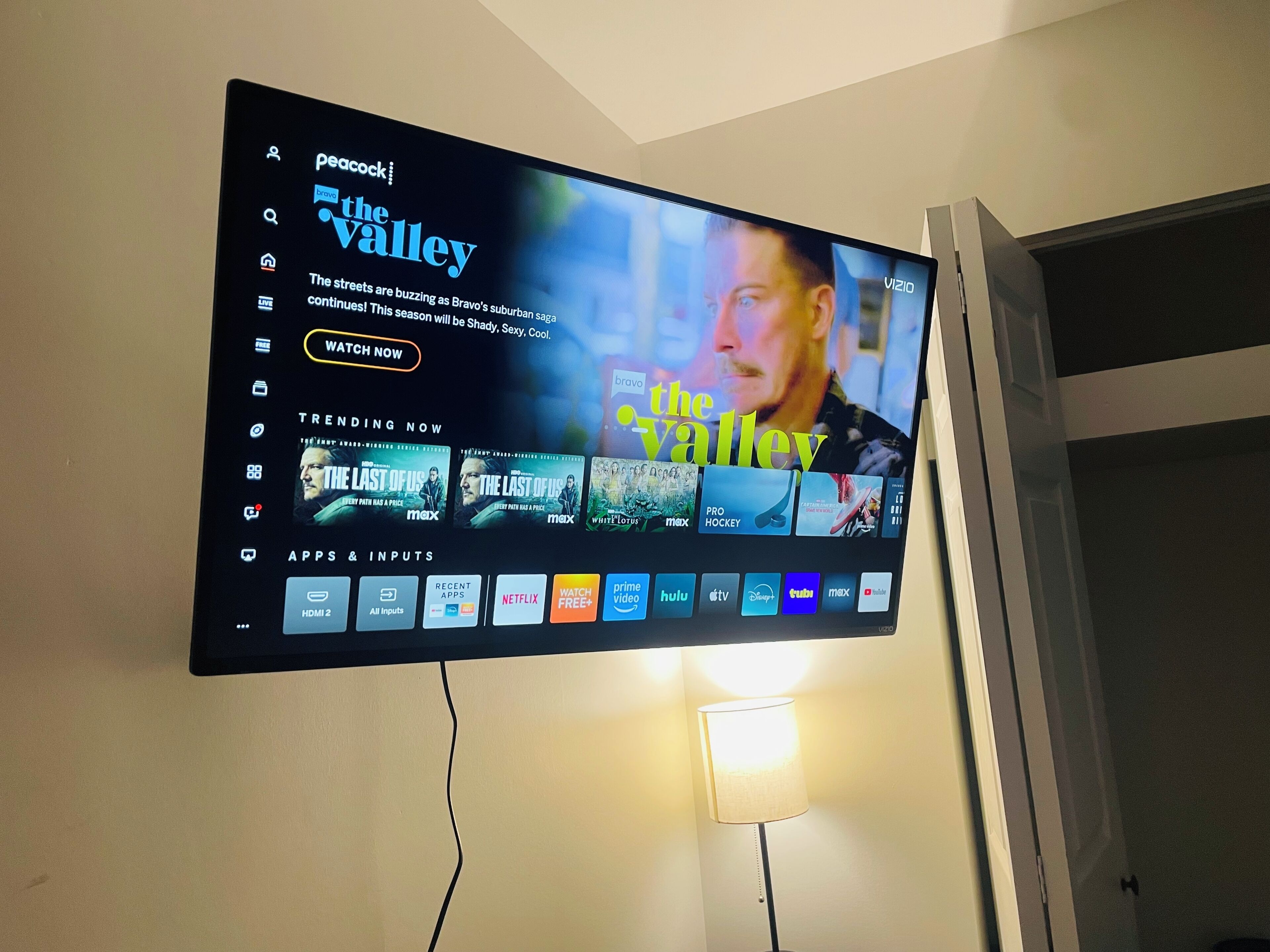 Una televisione a schermo piatto montata a parete mostra un'interfaccia di servizio di streaming con la serie 'The Valley' in evidenza.