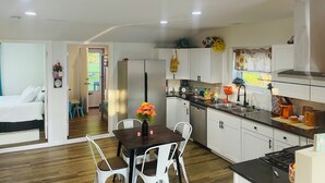 A modern kitchen with white cabinets, a central island, and a dining area with a table and chairs.