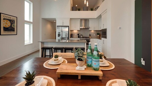 A modern kitchen with a central island, a dining area with a wooden table, and a hanging light fixture. - Stunning West End Home - Walkable Area (Nashville)