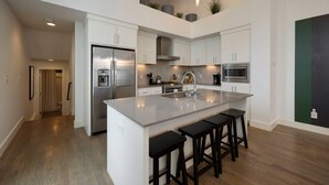 A modern kitchen with a central island, stainless steel appliances, and a high ceiling with recessed lighting. - Stunning West End Home - Walkable Area (Nashville)