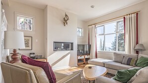 En stue med sofa, lænestol, fjernsyn og et lille bord.