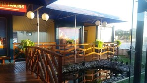 A restaurant with a wooden deck, outdoor seating, and a view of the ocean. - Eco hotel (Navegantes)