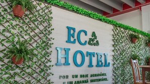 A sign for "EC HOTEL" with a green leafy wall design and potted plants. - Eco hotel (Navegantes)