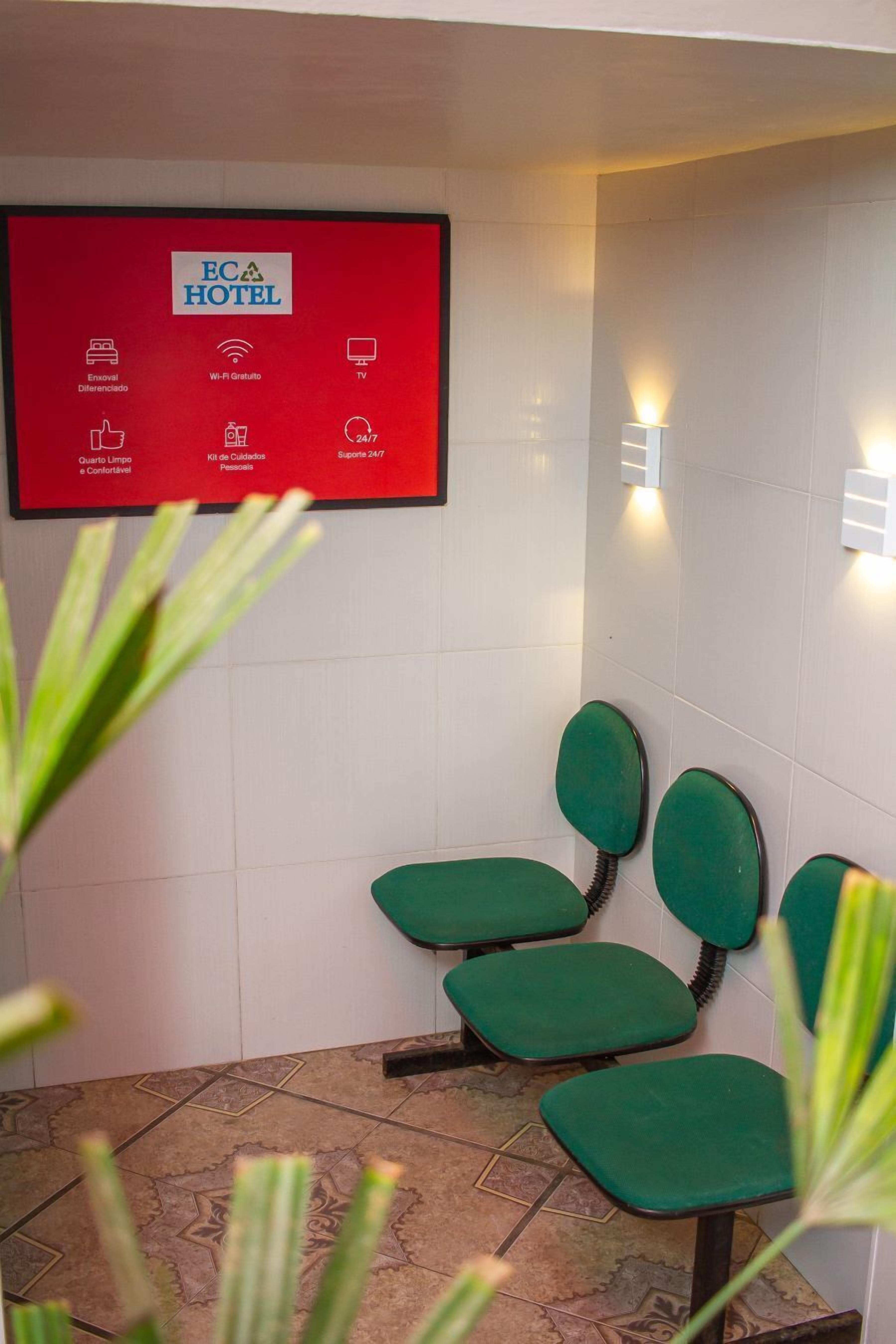 A hotel bathroom with a red sign listing amenities such as Wi-Fi, TV, and 24/7 support.