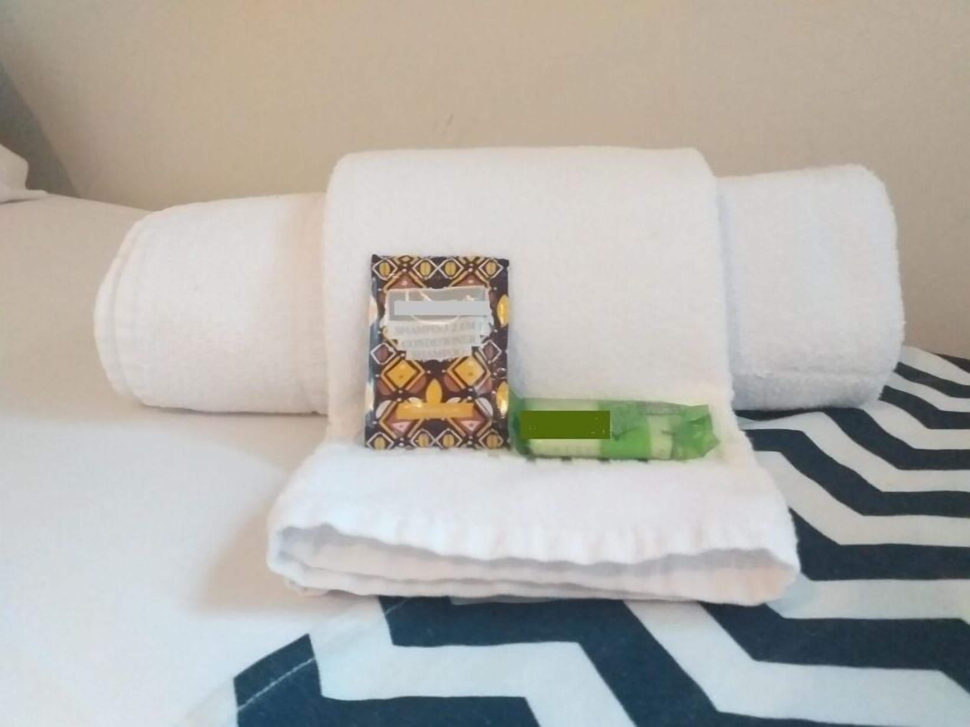 A neatly arranged bathroom with a white towel, a patterned soap bar, and a green bar of soap on a white towel.