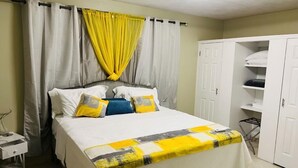 Quarto com cama, cortinas, guarda-roupa e mesa de cabeceira.