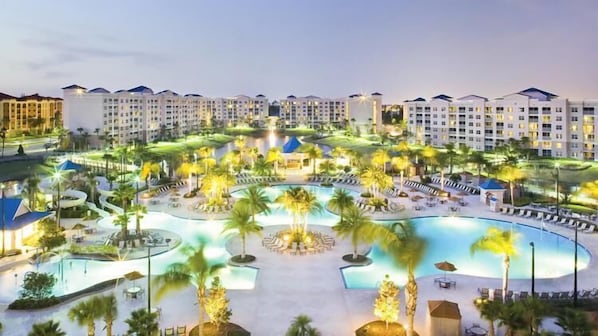 Relax by the resort's central pool surrounded by palm trees and lounge areas.