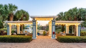Ein überdachter Außenbereich mit Stühlen und Tischen, umgeben von Palmen und Blick auf ein Gewässer.