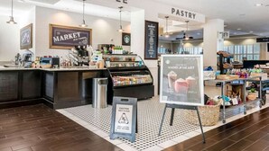 Ein Café mit Marktstand und Konditorei, inklusive Hinweisschild wegen nasser Böden und einer Präsentation handgefertigter Waren.