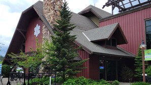 A building with a stone chimney, red siding, and a large window.