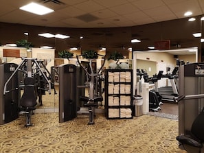 A gym with exercise equipment, a mirror, and a towel rack.