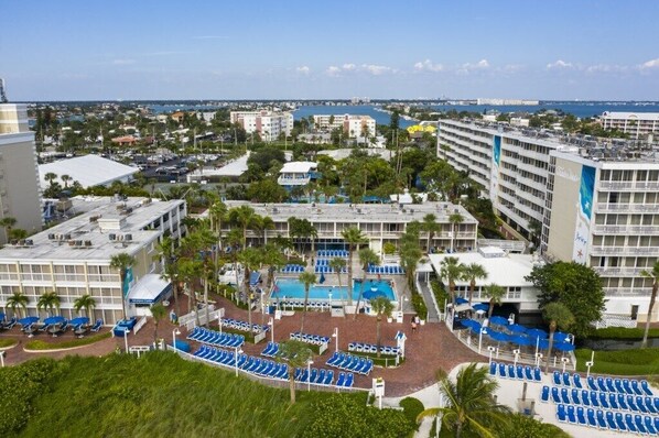 A hotel with multiple buildings, a swimming pool, and a view of the ocean.