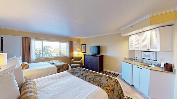 Une chambre d’hôtel avec deux lits, une télévision, un bureau et une kitchenette.