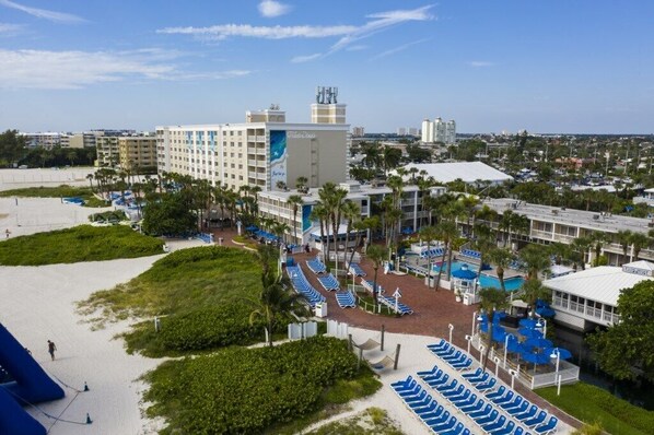 A hotel with a pool area, multiple floors, and a beach view.