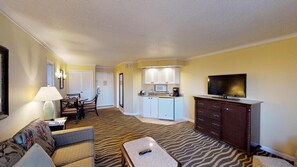 Habitación de hotel con sala de estar, cocina y televisor.