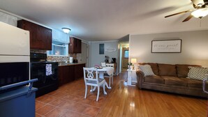 A kitchen with a dining area, a living room with a couch, and a ceiling fan. - Blue Ridge Mountain Cottage~1 minute from Parkway! (Newland)