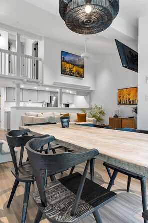 A modern kitchen with white cabinetry, a wooden dining table, and dark chairs. - Outpost: Pines 322 - Central Wilson Location (Wilson)
