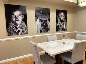 A dining area with a marble table and four grey upholstered chairs. - An Eclectic Home for the World Traveler (Washington)