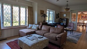 A living room with a sectional sofa, a coffee table, a chandelier, and a dining area with chairs. - Oliver Country House in the Wine Capital of Canada (Oliver)