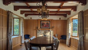 A dining room with a large wooden table, six chairs, a stone fireplace, wooden paneling, and a chandelier. - Oliver Country House in the Wine Capital of Canada (Oliver)