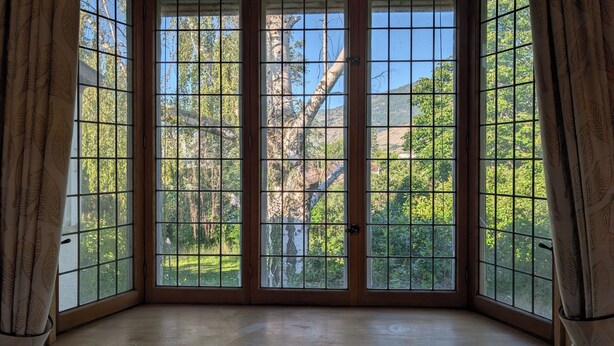 A bay window with a view of trees and a mountain. - Oliver Country House in the Wine Capital of Canada (Oliver)