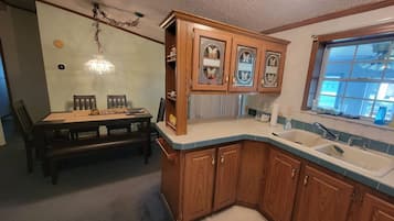 A kitchen with wooden cabinets, a sink, and a dining area with a table and chairs.