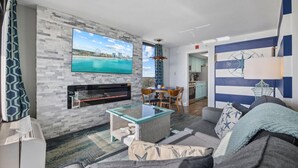 Ein Wohnzimmer mit Fernseher, Kamin, Sofa und einem Essbereich mit Stühlen.