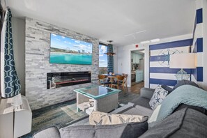 A living room with a TV, fireplace, sofa, and a dining area with chairs.