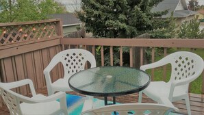 A deck with a glass table and white plastic chairs, surrounded by a wooden fence and trees. - "Almost Heaven" Palmer Lake, CO (#STR0419522) (Palmer Lake)