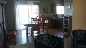 A living room with a black armchair, a dining area with wooden furniture, and a kitchen with a refrigerator and cabinets. - "Almost Heaven" Palmer Lake, CO (#STR0419522) (Palmer Lake)