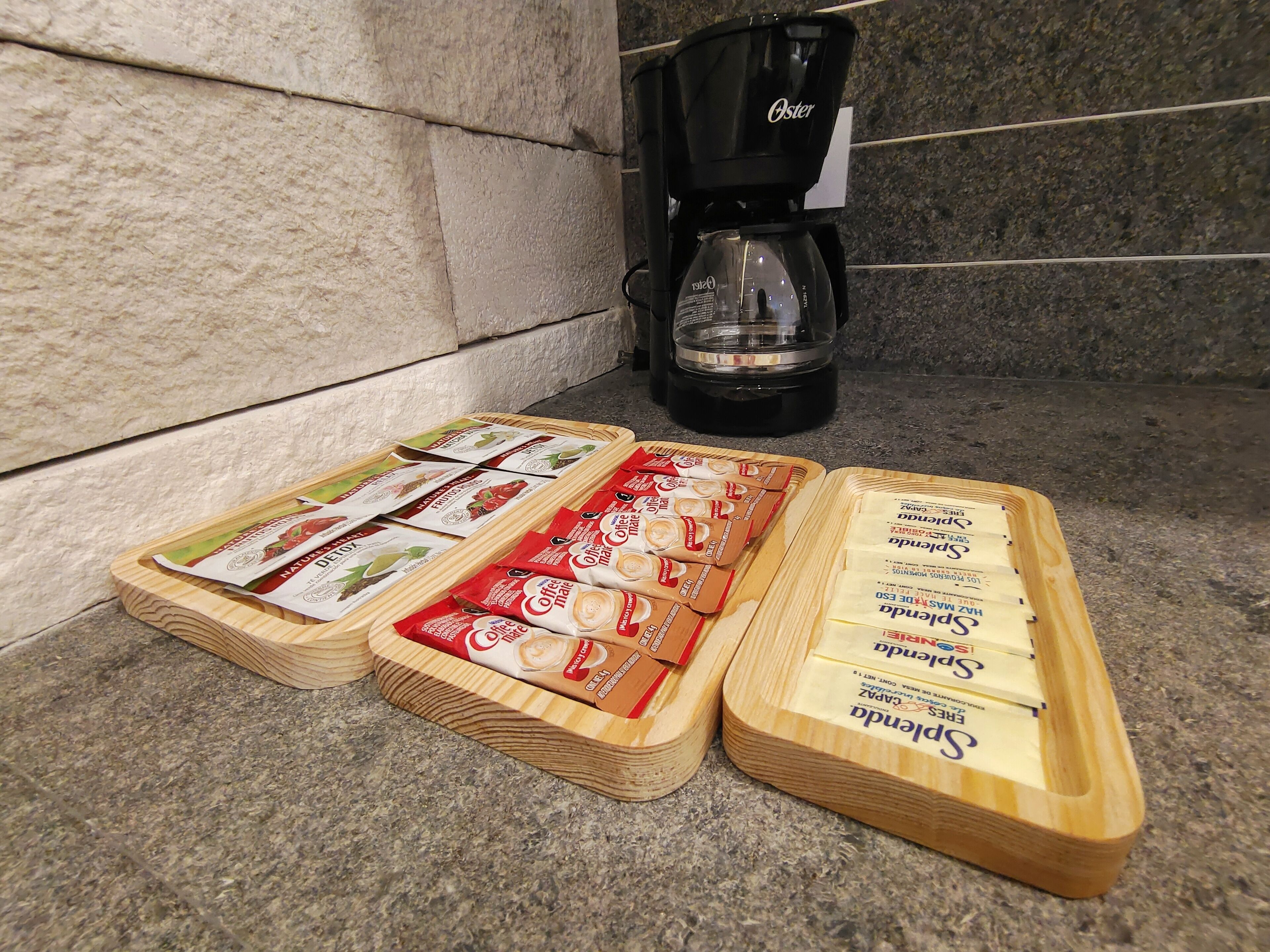 Three wooden trays with coffee pods on a kitchen counter.