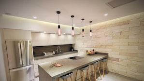 Eine moderne Küche mit einem Edelstahl-Kühlschrank, einer Granit-Arbeitsplatte und einer Steinrückwand.