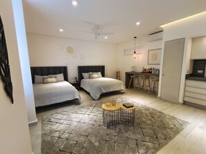 A modern bedroom with two beds, a desk, and a bar stool. - 1st Luxury Warehouse (Cancun)