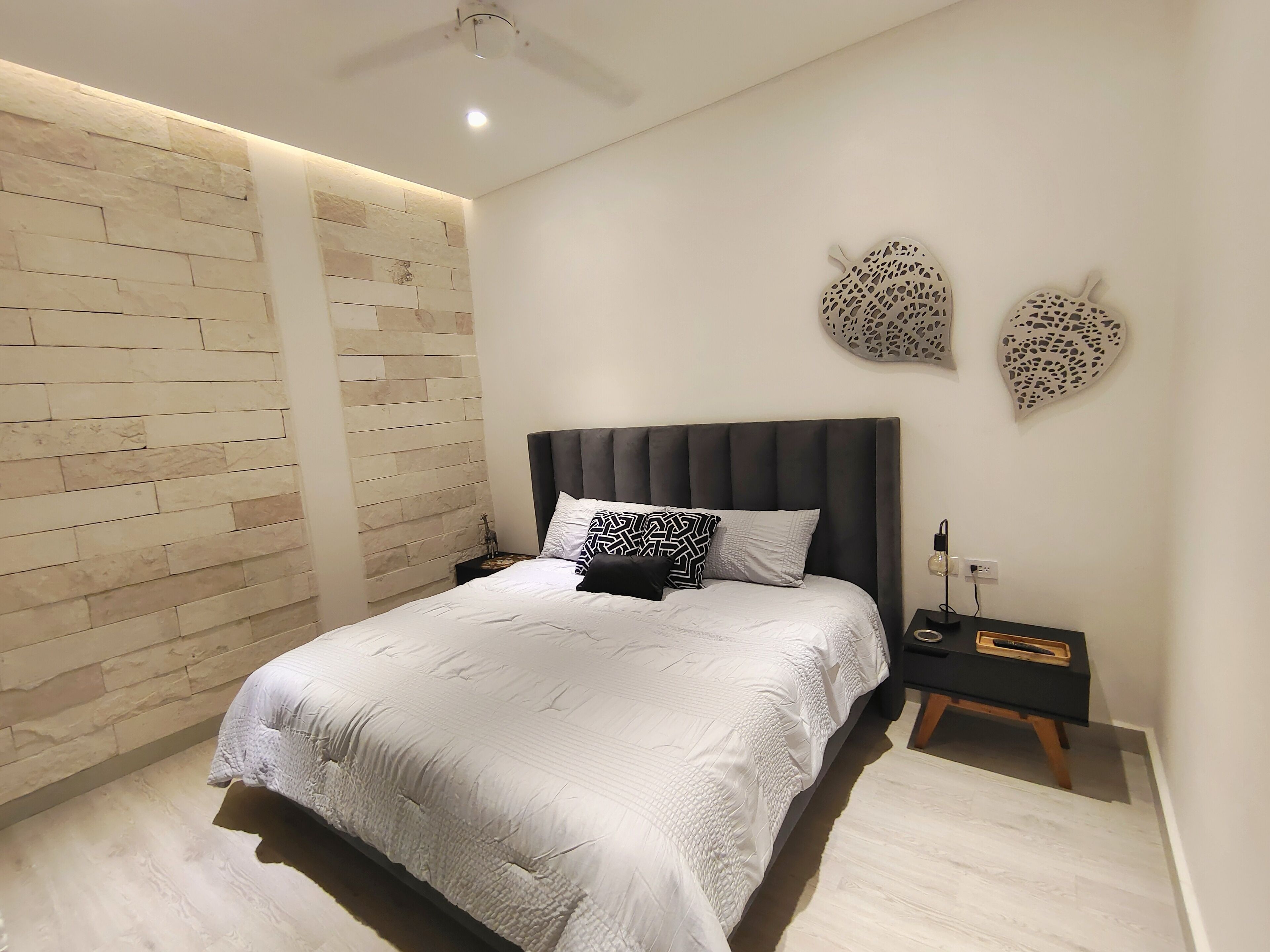 A modern bedroom with a large bed, a nightstand, and decorative wall art.