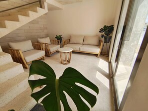 A modern living room with a staircase, a round coffee table, and a large plant. - 1st Luxury Warehouse (Cancun)