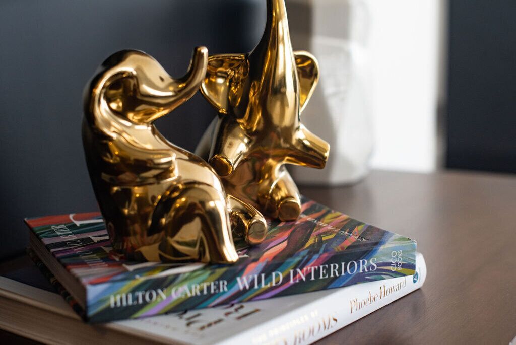 A book titled 'Hilton Carter Wild Interiors' with a decorative golden elephant figurine on top.