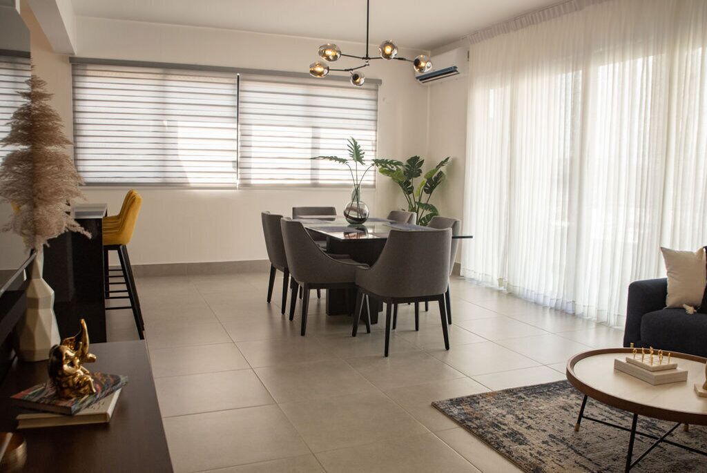 A modern living room with a dining area, featuring a chandelier, a sofa, and a coffee table.